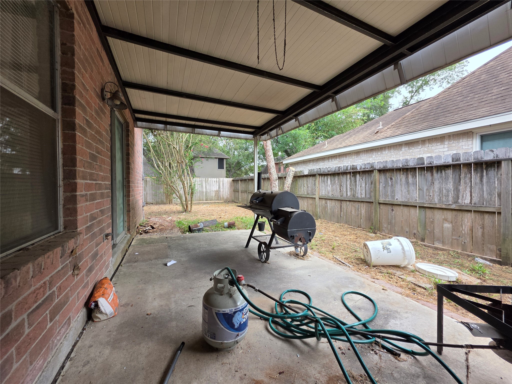 15615 Fern Ridge Drive Houston, TX 77084 - Photo 26 of 31 Covered patio with ample space for outdoor activities, featuring a brick exterior and a view of the fenced backyard. Perfect for grilling and relaxing.