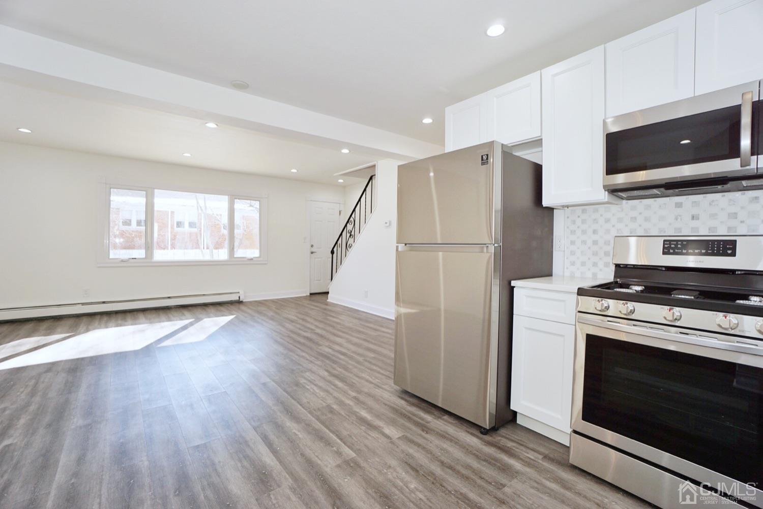 106 Ridge Road Colonia, NJ 07067 - Photo 4 of 44 a kitchen with stainless steel appliances a stove a microwave oven cabinets and wooden floor