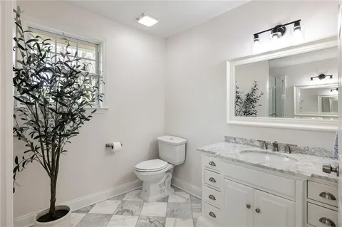 a bathroom with a granite countertop sink toilet and mirror