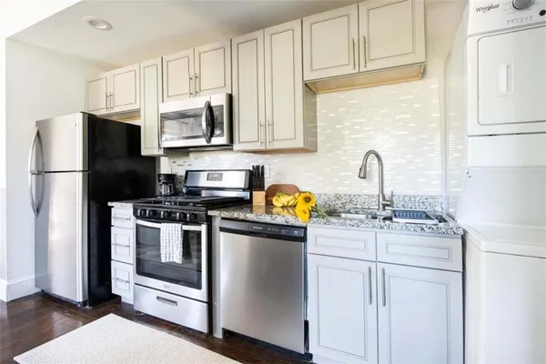 a kitchen with stainless steel appliances granite countertop a refrigerator sink stove and white cabinets