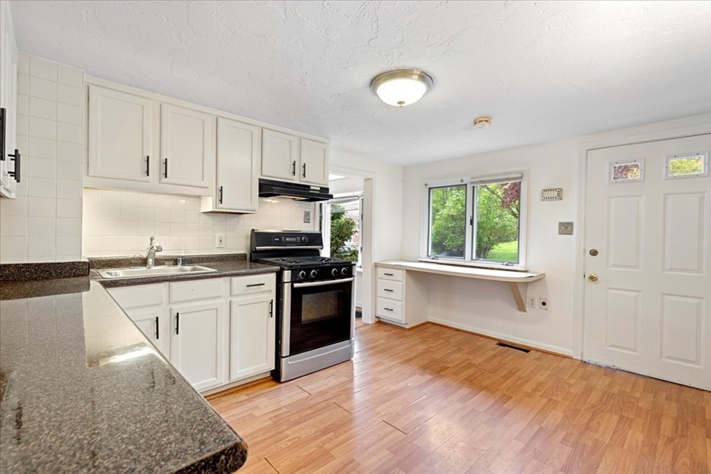 203 High Street, Unit 203 Hingham, MA 02043 - Photo 20 of 42 a kitchen with granite countertop a stove top oven sink and cabinets