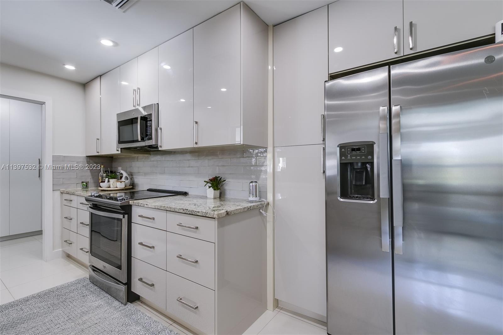 3820 Northwest 7th Avenue Deerfield Beach, FL 33064 - Photo 18 of 37 a kitchen with stainless steel appliances granite countertop a refrigerator a stove and a sink with wooden floor