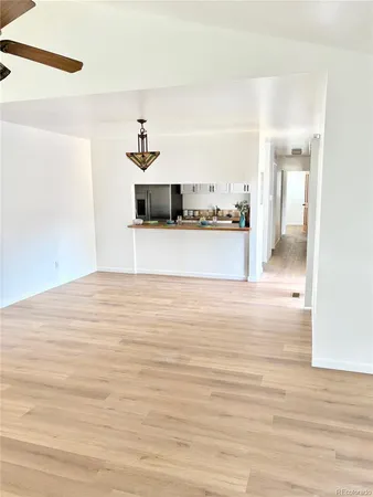 a view of a room with a ceiling fan and hardwood floor