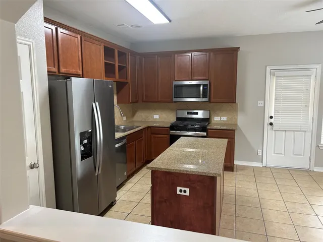 a kitchen with stainless steel appliances granite countertop a refrigerator a stove a sink a microwave and cabinets