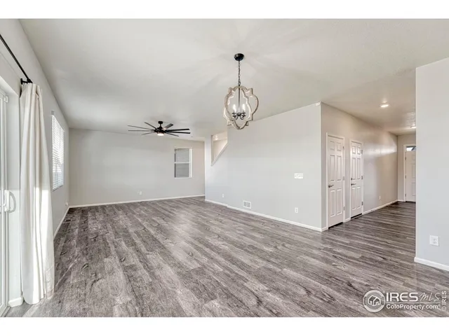 a view of a big room with wooden floor a ceiling fan and windows