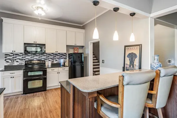 a kitchen with kitchen island a stove a table and chairs