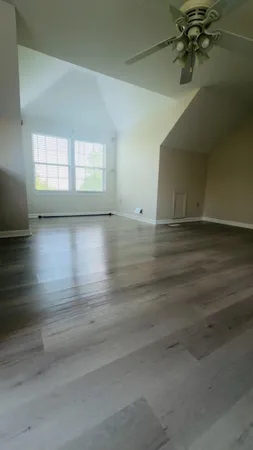 an empty room with wooden floor and windows