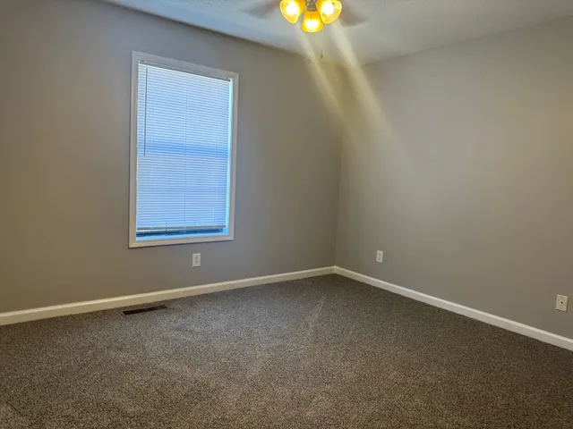 an empty room with a chandelier fan and a window