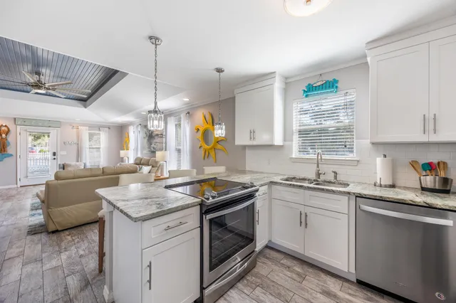 a kitchen with granite countertop stainless steel appliances a sink stove and cabinets