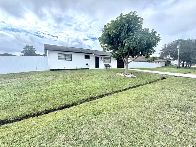 a view of a house with a big yard and large trees