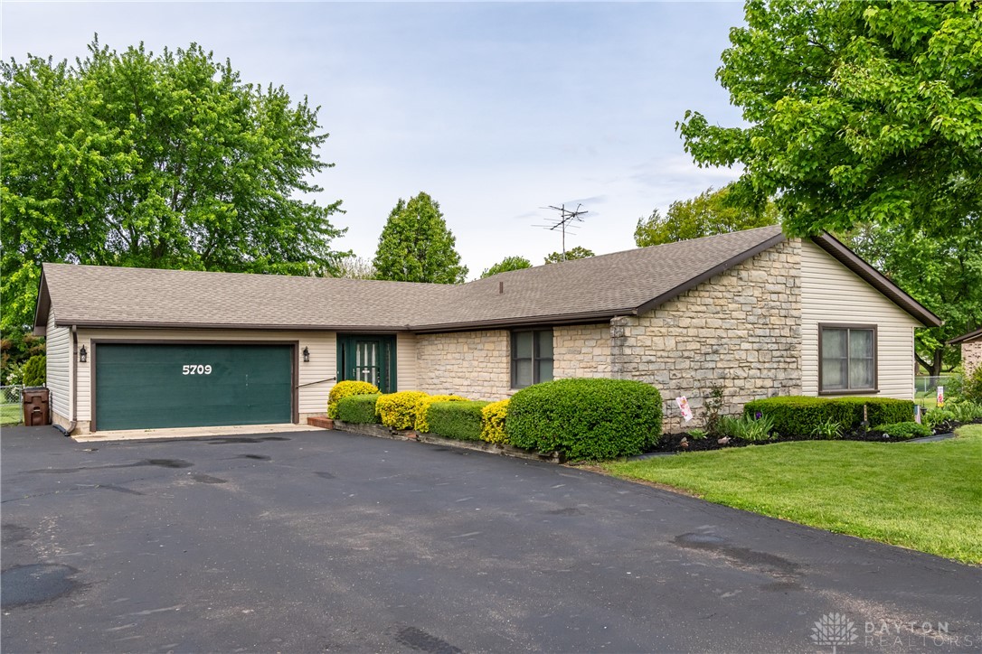 This ranch-style home features a spacious driveway and an attached garage.