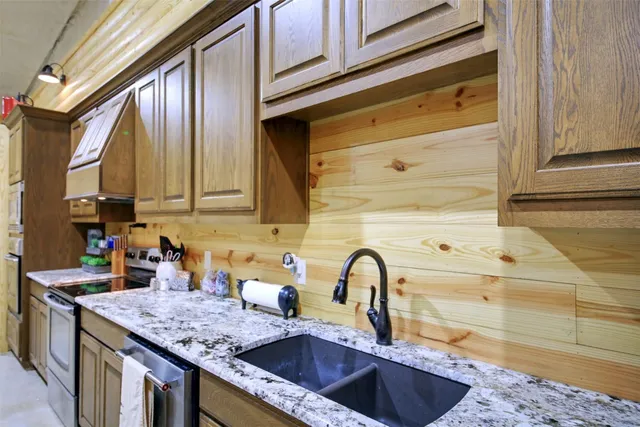 a kitchen with stainless steel appliances granite countertop sink stove refrigerator and cabinets