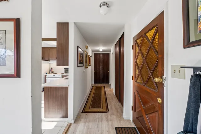 a view of a hallway with wooden floor and a living room