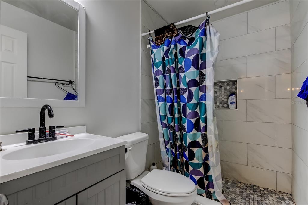 4532 Devonshire Road Tampa, FL 33634 - Photo 18 of 37 a bathroom with a sink a toilet and shower curtain