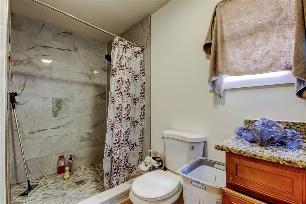 4532 Devonshire Road Tampa, FL 33634 - Photo 24 of 37 a bathroom with a granite countertop toilet and a shower