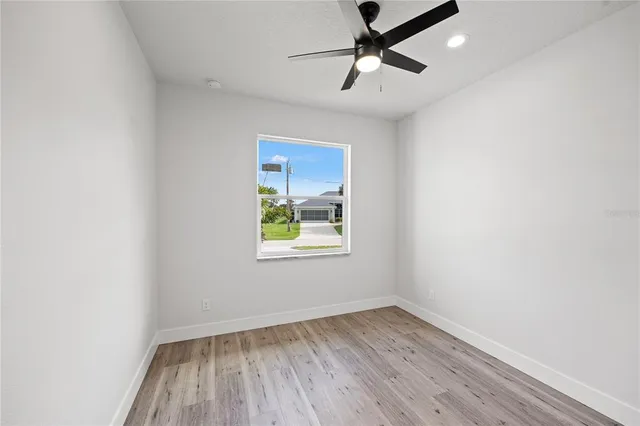 an empty room with a window and ceiling fan