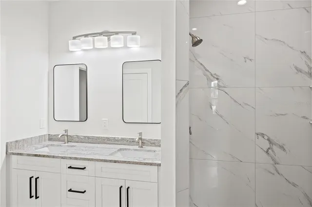 a bathroom with double granite countertop a sink a toilet a mirror and vanity