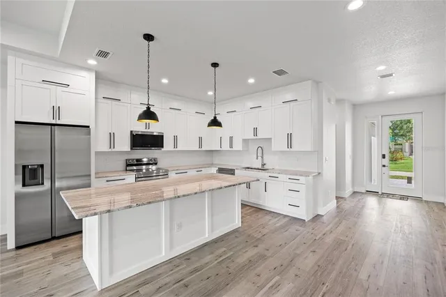 a large kitchen with cabinets wooden floor and stainless steel appliances