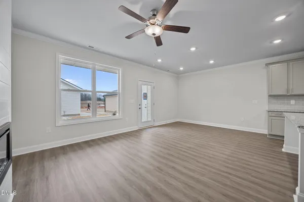 an empty room with chandelier fan and windows
