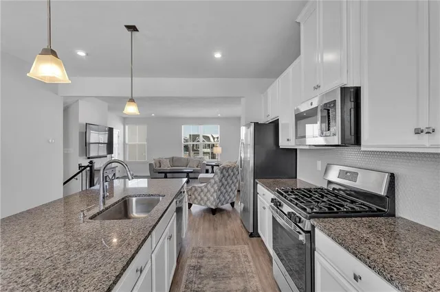 a kitchen with stainless steel appliances granite countertop a sink a stove and a wooden floors