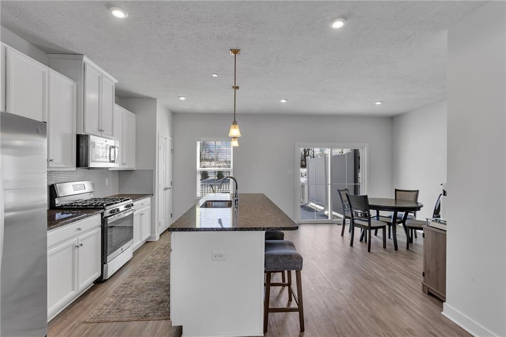 7406 Chestnut Way Gibsonia, PA 15044 - Photo 8 of 42 a kitchen with stainless steel appliances granite countertop a stove top oven a sink a dining table and chairs with wooden floor
