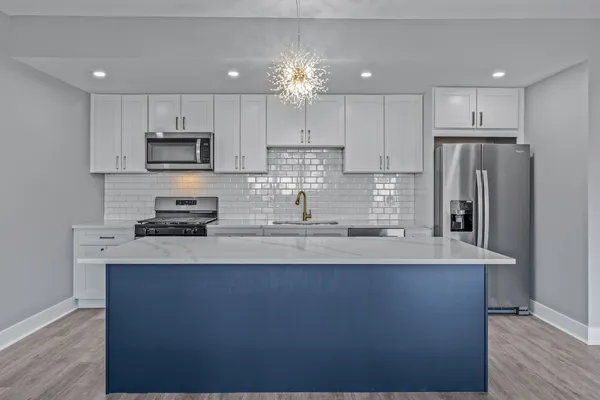 a large kitchen with stainless steel appliances a refrigerator stove a sink and a microwave