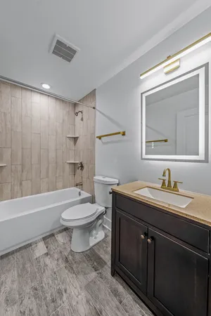 a bathroom with a toilet a sink a mirror a bathtub and shower