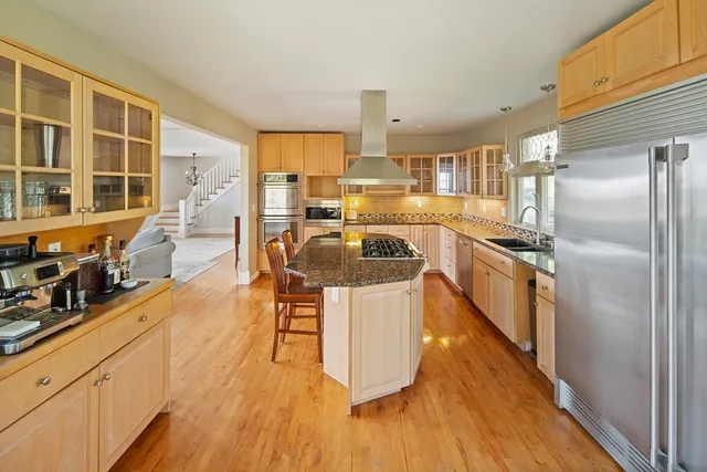 a kitchen with stainless steel appliances granite countertop a refrigerator a stove and a wooden floors