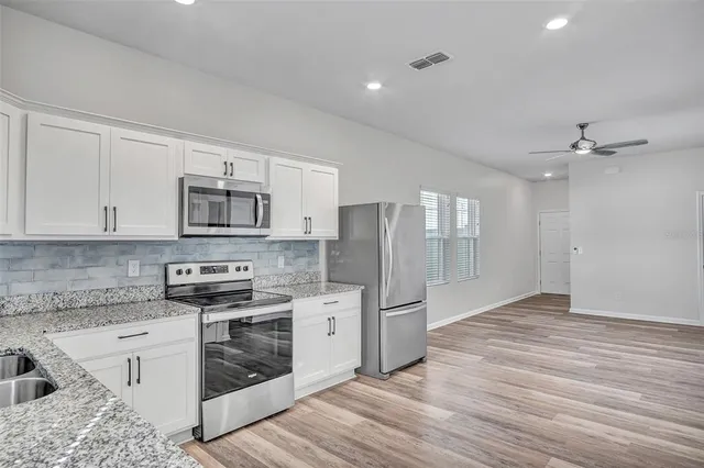 a kitchen with stainless steel appliances kitchen island granite countertop a refrigerator stove and sink