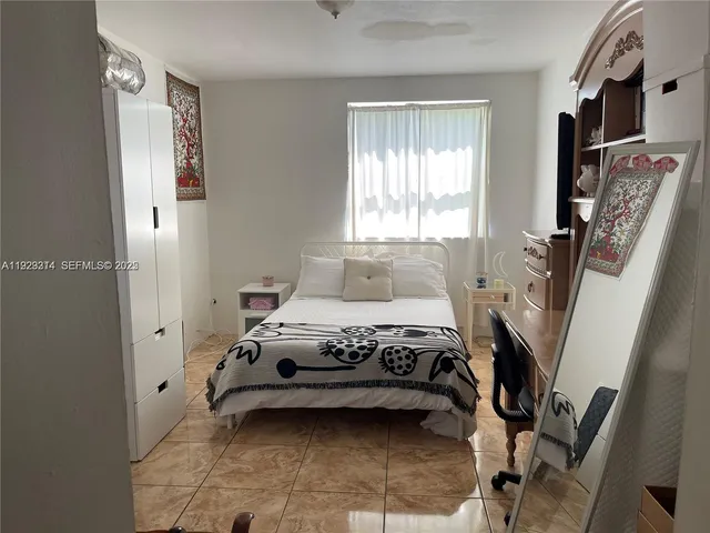 a bedroom with a bed a flat screen tv and a window