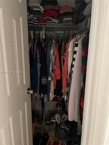 a view of walk in closet with clothes and shoes