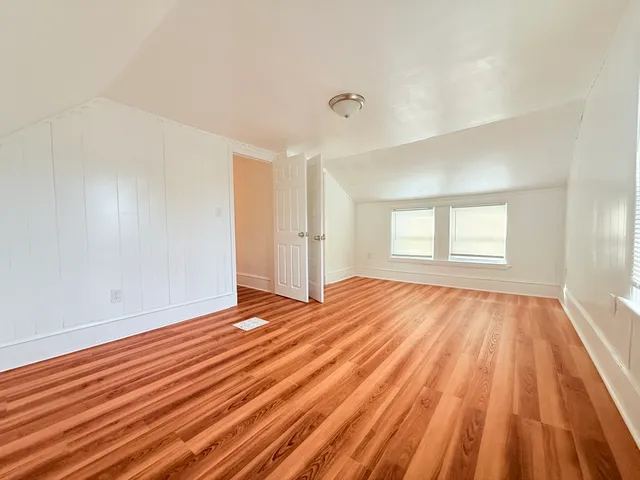 a view of an empty room with wooden floor and window