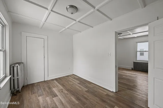 an empty room with wooden floor and a ceiling fan
