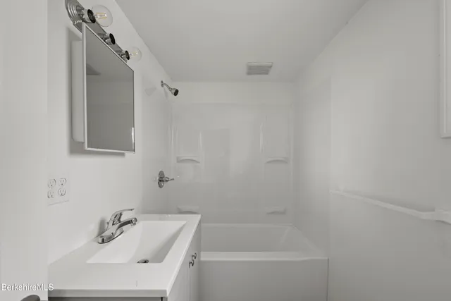 a white bath tub sitting next to a white sink and vanity