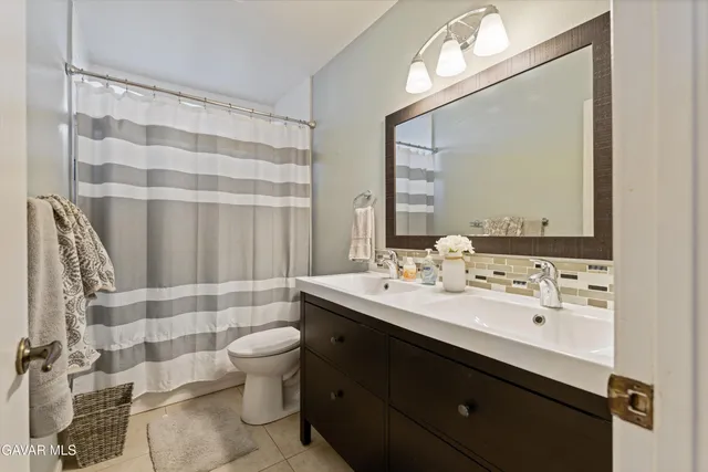 a bathroom with a double vanity sink toilet and mirror
