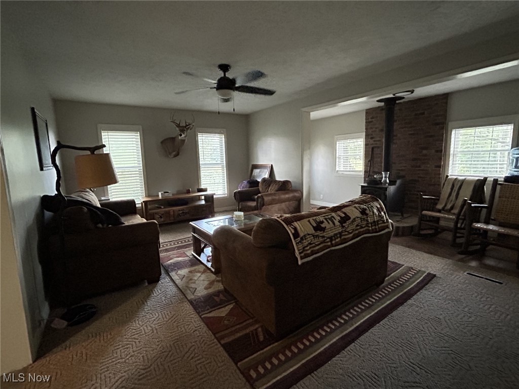 4853 Leon Road Andover, OH 44003 - Photo 16 of 33 Living room with plenty of natural light, ceiling fan, a wood stove, and carpet floors