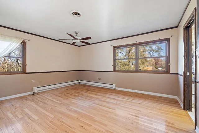 a view of an empty room with a window and wooden floor