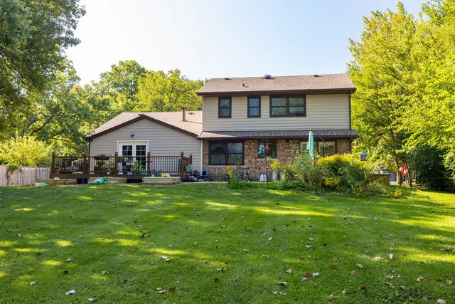 a view of a house with a big yard potted plants and large tree