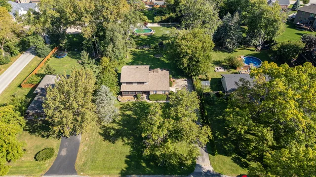 an aerial view of residential house with outdoor space and trees all around