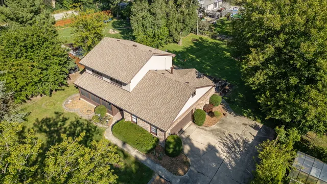 an aerial view of a house with a yard and trees all around