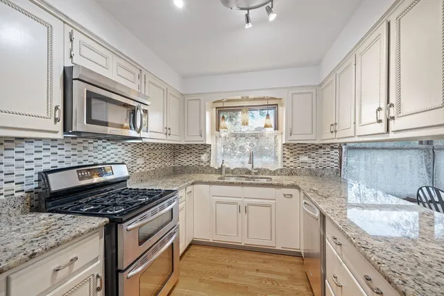 a kitchen with granite countertop a sink stove and cabinets