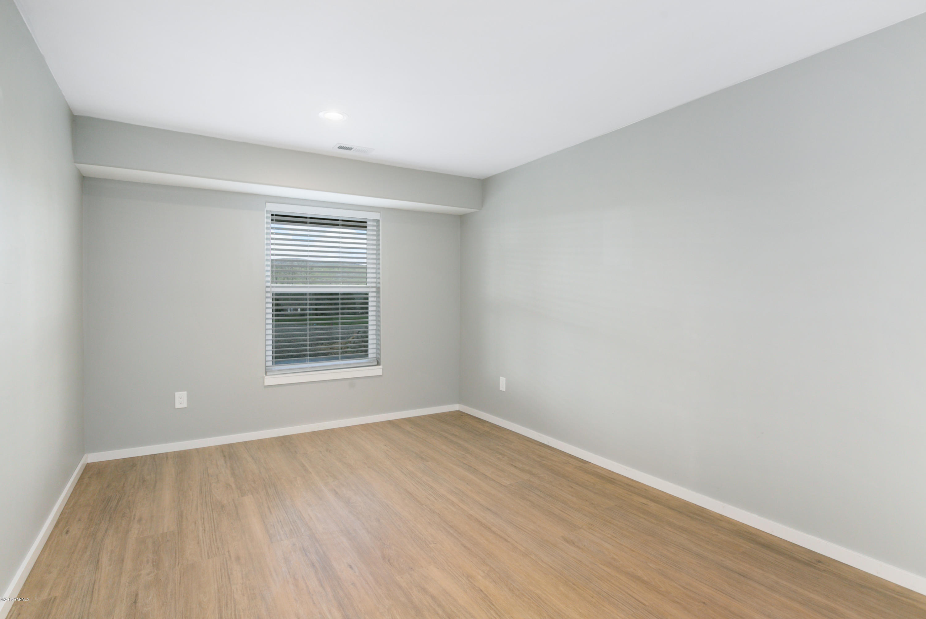 640 Winchester Road Yakima, WA 98908 - Photo 22 of 26 a view of an empty room with wooden floor and a window