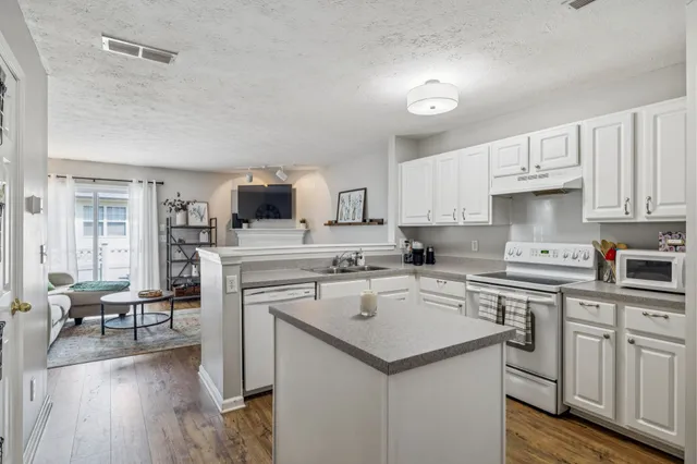 a kitchen with a sink a stove cabinets and wooden floor
