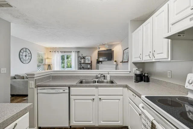 a kitchen with kitchen island granite countertop a sink a stove and cabinets