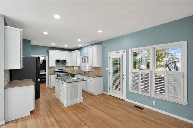 a kitchen with stainless steel appliances kitchen island granite countertop a refrigerator stove and sink