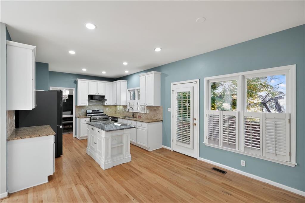 10950 Regal Forest Drive Suwanee, GA 30024 - Photo 29 of 52 a kitchen with stainless steel appliances a stove top oven a refrigerator a sink and dishwasher with wooden floor