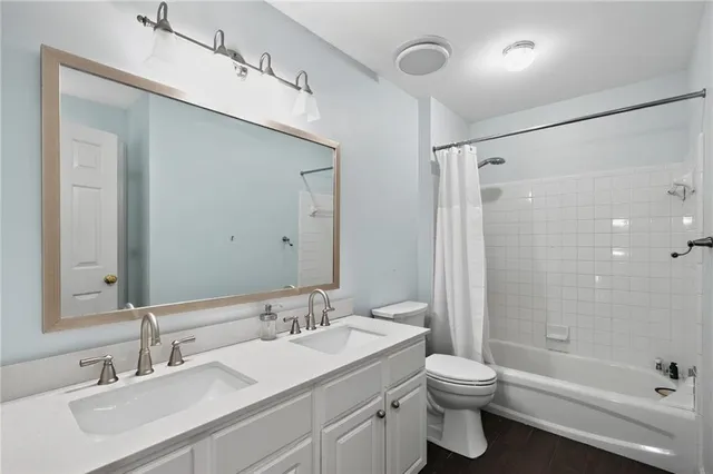 a bathroom with a granite countertop sink a toilet and shower