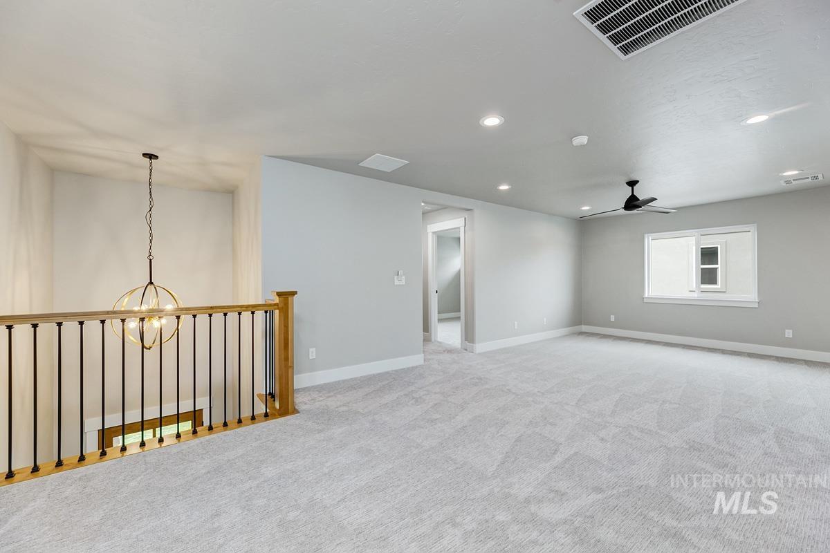 13544 North Ruffed Grouse Way Boise, ID 83714 - Photo 19 of 44 Empty room featuring a chandelier, recessed lighting, light carpet, and a ceiling fan