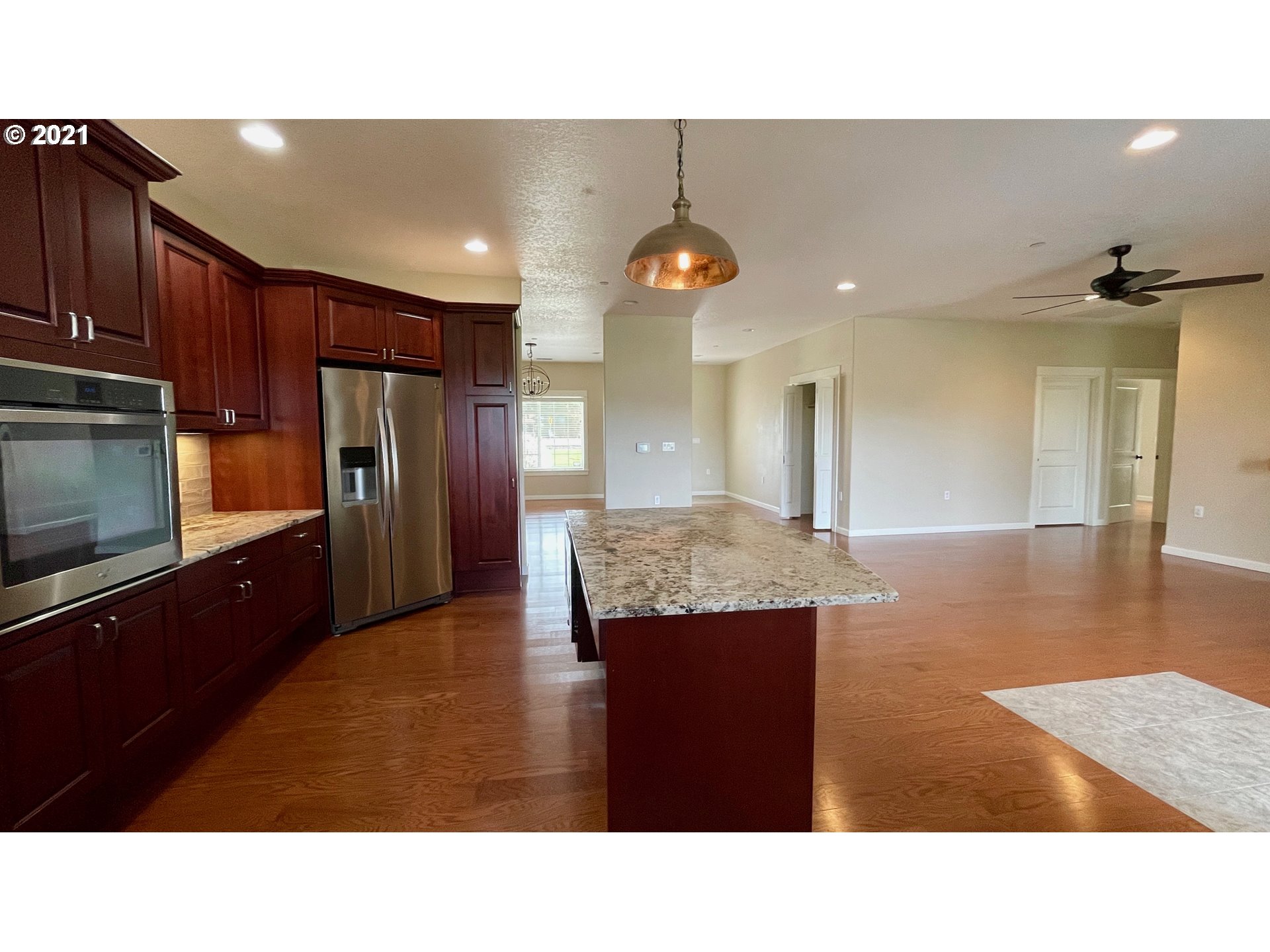 8765 Southwest River Road Hillsboro, OR 97123 - Photo 5 of 31 a kitchen with stainless steel appliances kitchen island granite countertop a refrigerator a stove and a sink with wooden floor