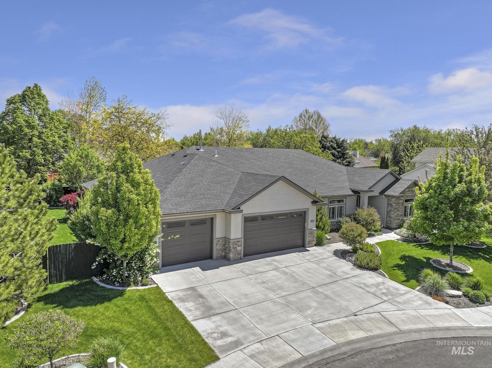Contemporary ranch-style residence featuring a multi-car driveway, stone accents, two garage doors, and a dark shingle roof